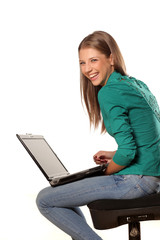 smiling girl sitting on a chair and holding laptop on her legs