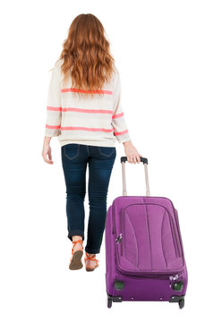 back view of walking  woman  with suitcase.