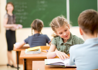 Teacher and school kids in classroom at lesson