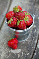 strawberries in a bucket on wooden garden table