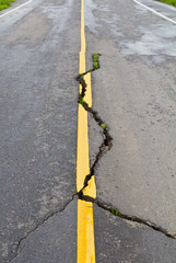Cracks on asphalt the yellow line dividing lanes with grass