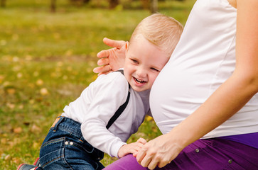Happy smiling child near pregnant mom tummy