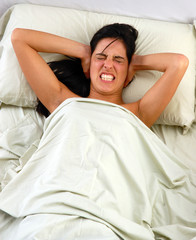 mujer en la cama molesta por ruido,dolor de cabeza