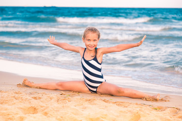 Beautiful little girl excercising on the beach