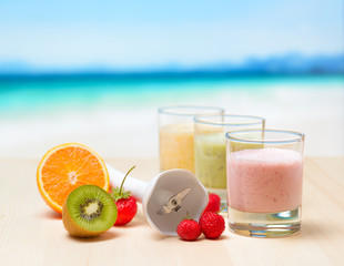 Fruit smoothie on wooden table on tropical beach