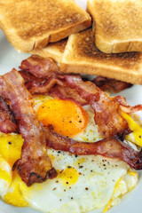 Fried egg and crispy bacon with toasts, vertical