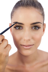 Obraz premium Content woman applying make up on her eyebrows