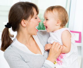 Happy Smiling Mother and Baby kissing and hugging at Home