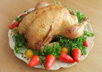Roasted whole chicken on a plate with vegetables