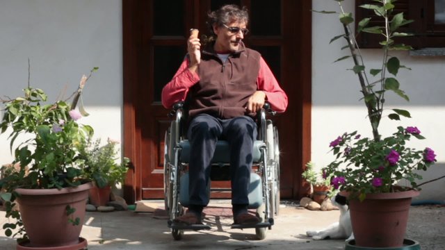 happy man on a wheelchair eating an icecream