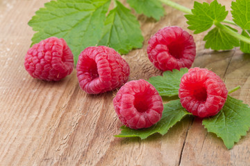 Raspberries with leaves over wooden background