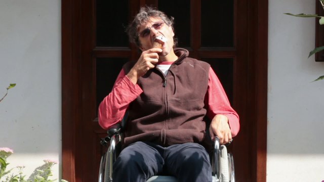 man on a wheelchair eating an icecream
