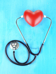 Stethoscope and heart on wooden table close-up