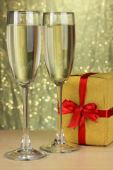 Glasses of champagne with gift box on shiny background