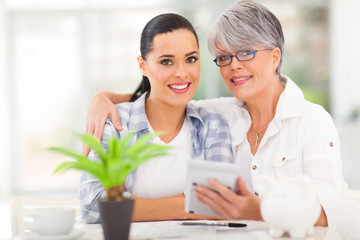 senior mother helping daughter calculate her finances
