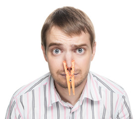Man with orange clothespin on his nose - bad smell concept.
