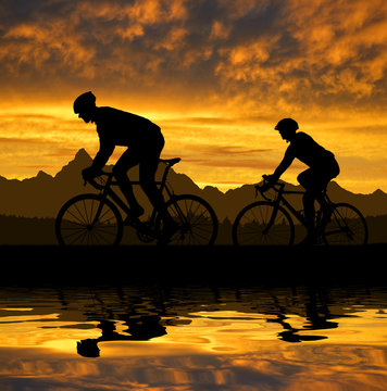 silhouette of the cyclists riding a road bike at sunset