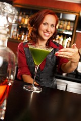 Cheerful barmaid with cocktail behind bar counter