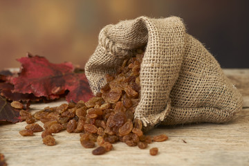 Golden raisins in burlap bag over wooden table