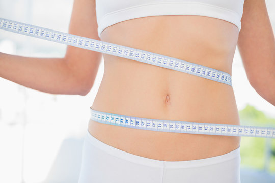 Slender woman measuring her waist during diet