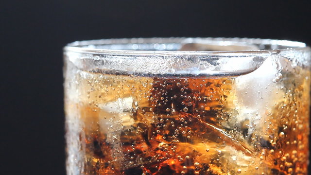 cola and ice in glass, bubble float, black background