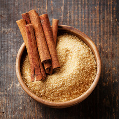 Cinnamon sticks and cane sugar on wooden background