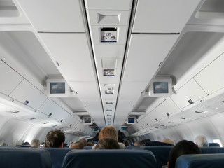 Fototapeta premium Airplane interior - people sitting on seats