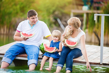 Fototapeta na wymiar happy family on picnic in the green park with lake