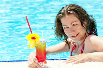 charming brunette in the pool holding a glass of cocktail