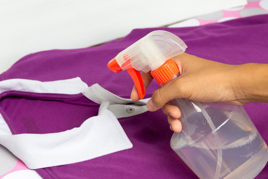 Spraying a casual cloth with laundry detergent in spray bottle.