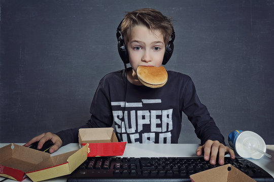 enfant jouant sur ordinateur en mangeant hamburger