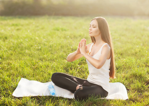 Attractive woman practices yoga in nature. Lotus Pose.
