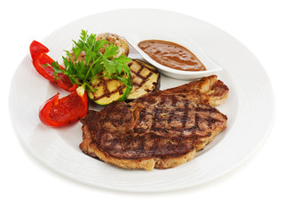 Grilled steaks, baked potatoes and vegetables on white plate.