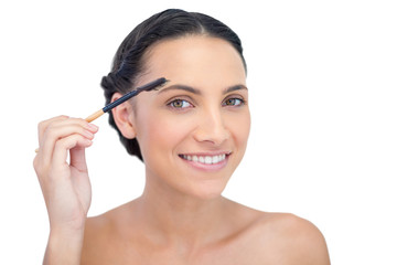 Smiling young brunette using eyebrow brush