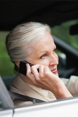 Peaceful businesswoman on the phone driving classy car