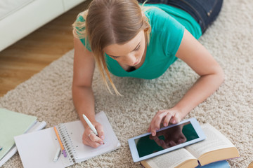 Blonde woman lying on floor using tablet to do her assignment