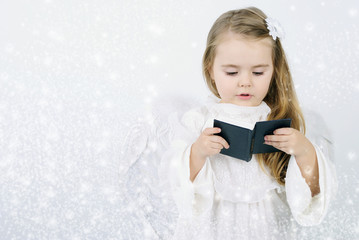 A beautiful little girl angel with a book