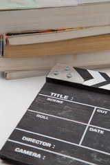 wooden clapper board with a pile of books