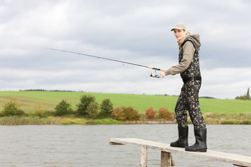 woman fishing on pier at pond