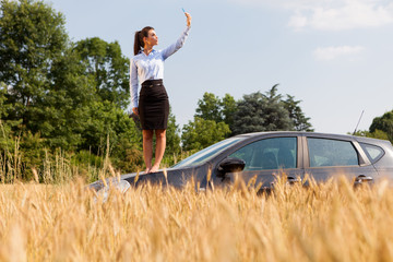 Businesswoman searching phone signal while standing on her car