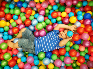 Fototapeta na wymiar Happy child playing with colorful plastic balls