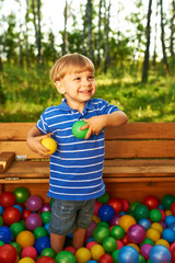 Happy child playing with colorful plastic balls