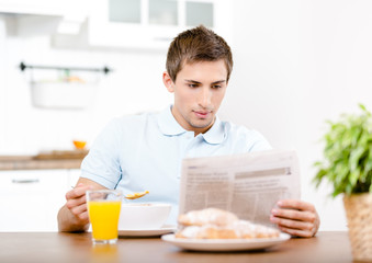 Reading newspaper man eats light breakfast 