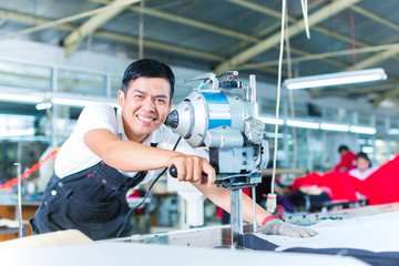 Asian worker using a machine in a factory