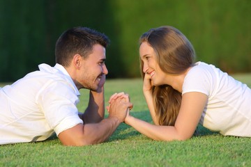 Couple flirting and looking each other lying on the grass