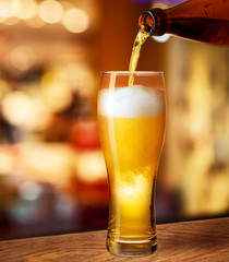 pouring beer in glass on bar or pub desk