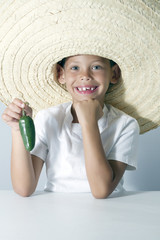 Niño rubio con sombrero mejicano muestra un pimiento