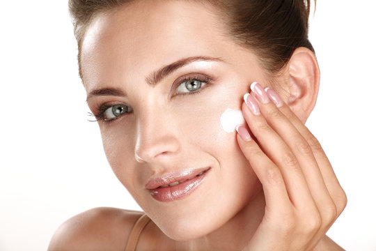 beautiful model applying cosmetic cream treatmen on her face