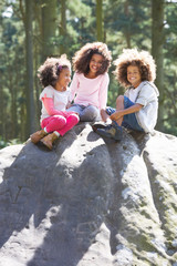 Three Children Climbing On Rock In Countryside