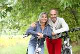 Cheerful senior couple with bicycle in country path